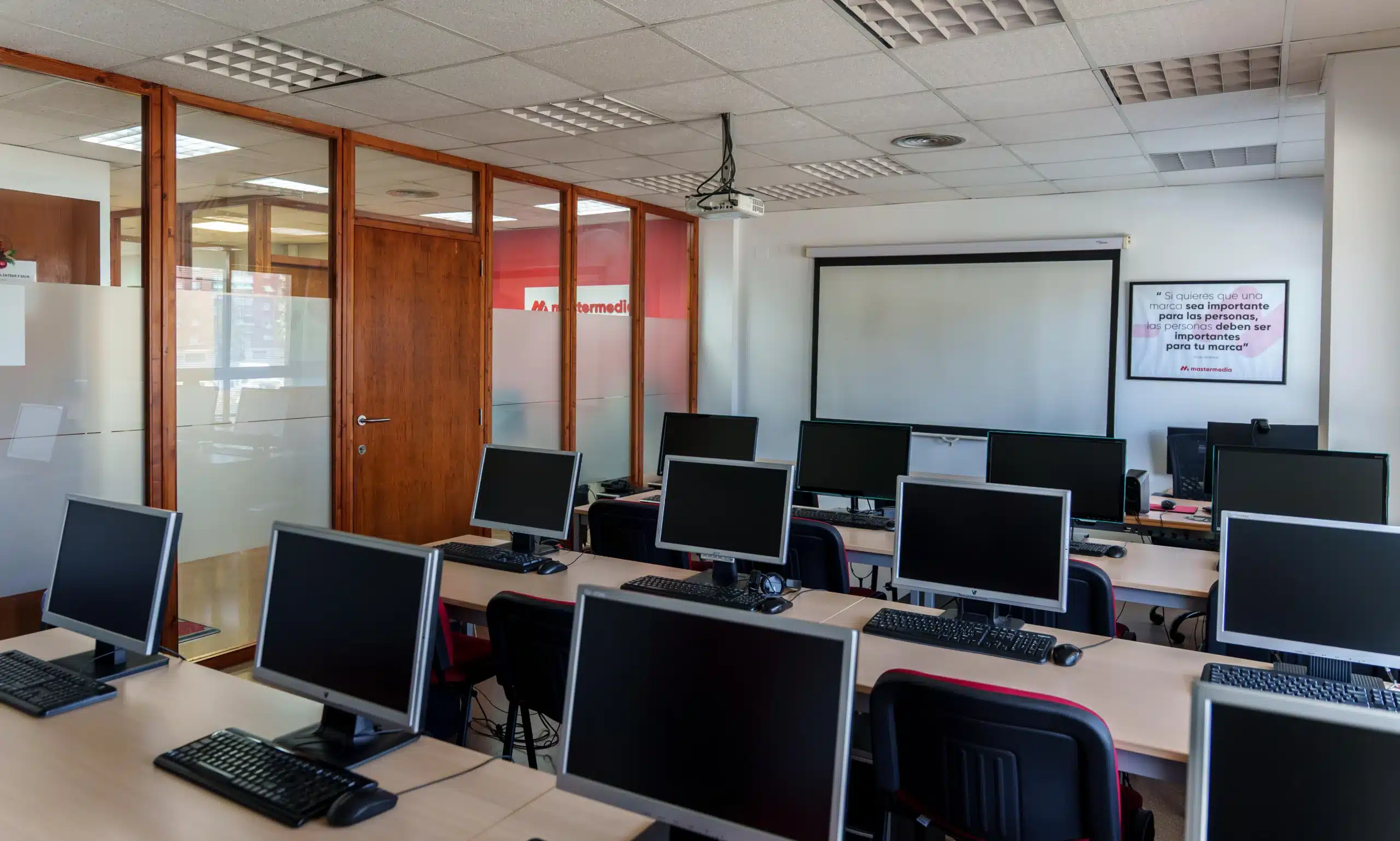 Aula principal de Escuela Mastermedia en Valencia con ordenadores y pantalla de proyección
